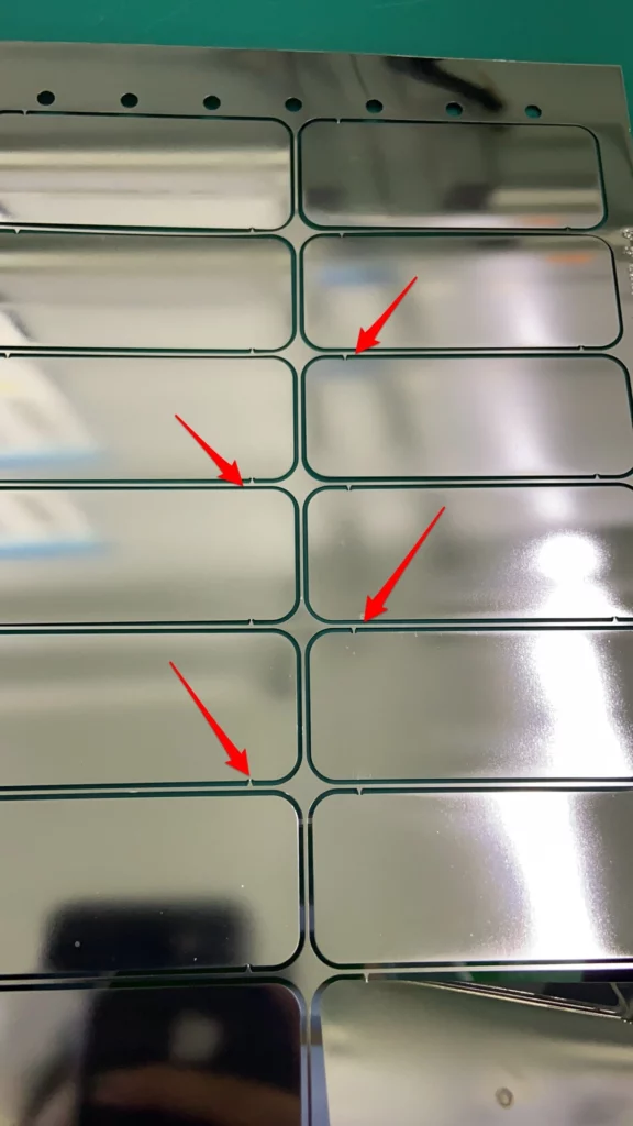 Retaining_tabs_connecting_photo-etched_metal_parts_to_a_production_sheet
